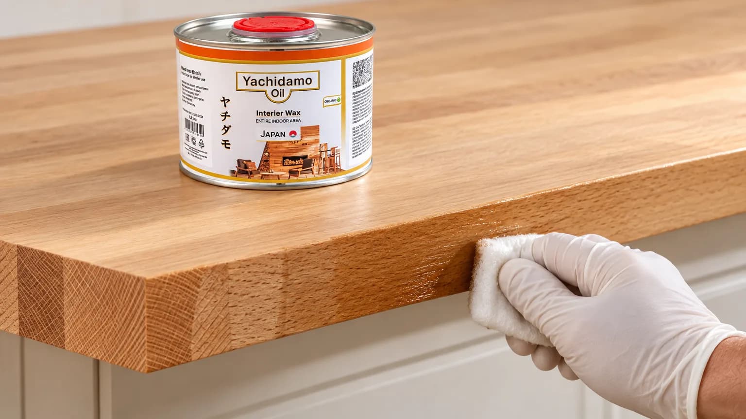 Банка Yachidamo Oil Interior Wax стоит на буковой столешнице, торец и нижнюю кромку которой промасливают белой салфеткой.